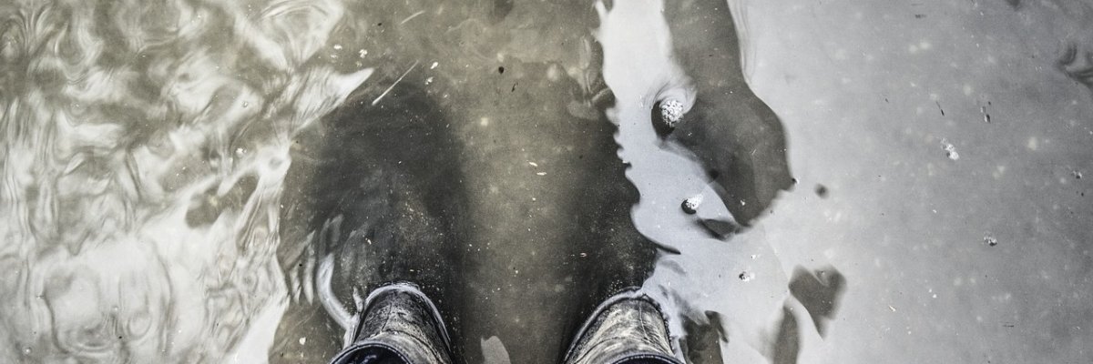 Person steht mit Gummistiefeln im Wasser