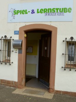 Spiel- und Lernstube im Winzler Viertel Blick auf den Eingang in die Spiel- und Lernstube im Winzler Viertel mit großem, einladenden Eingangsschild