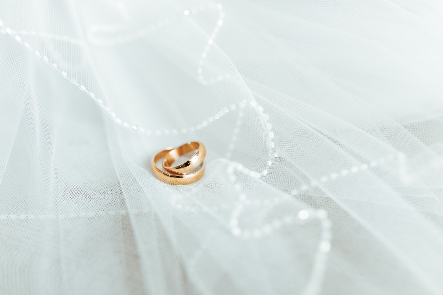 Trauringe Zwei goldene Ringe liegen auf einem zarten Brautschleier