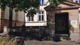 KiTa Wittelsbach Abgebildet ist der Eingangsbereich der Kita mit Eingangstür und buntem Kitaschild