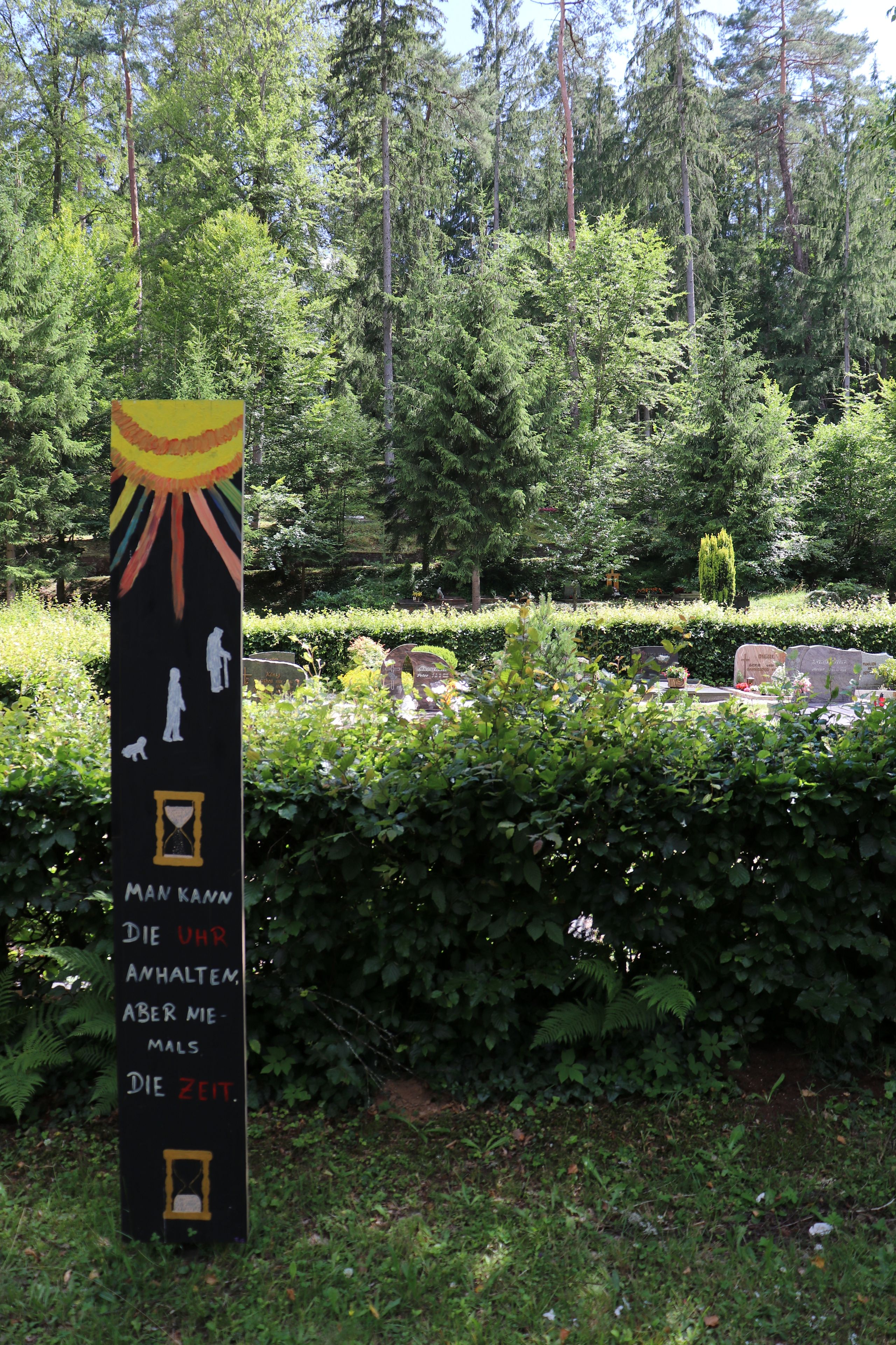 Blick auf Talabteilung des Waldfriedhofs mit künstlerisch gestalteter Tafel mit Lebensweisheiten