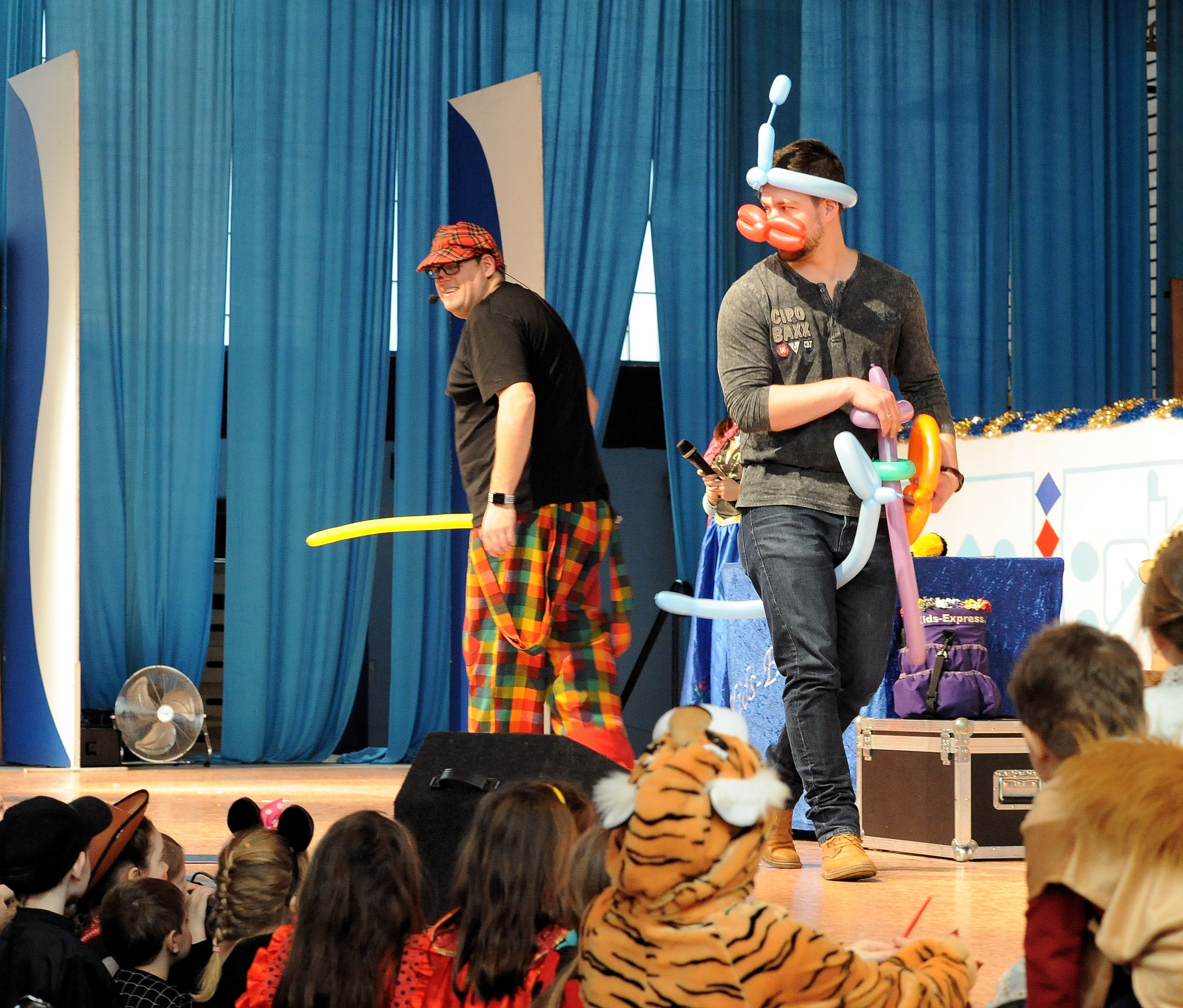 Kinderfasching Zu sehen sind zwei Männer auf der Bühne mit Ballonfiguren