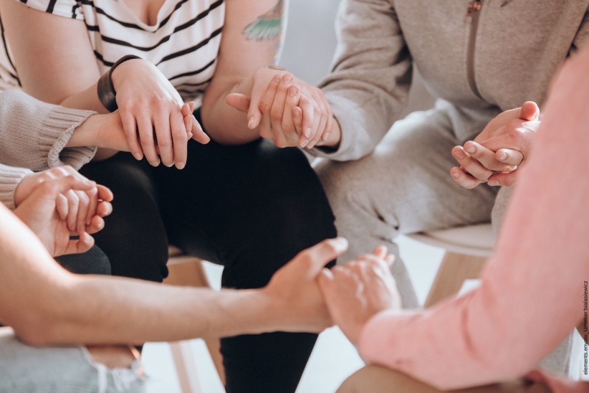 Selbsthilfegruppe Menschen sitzen in einem Kreis und halten sich die Hände