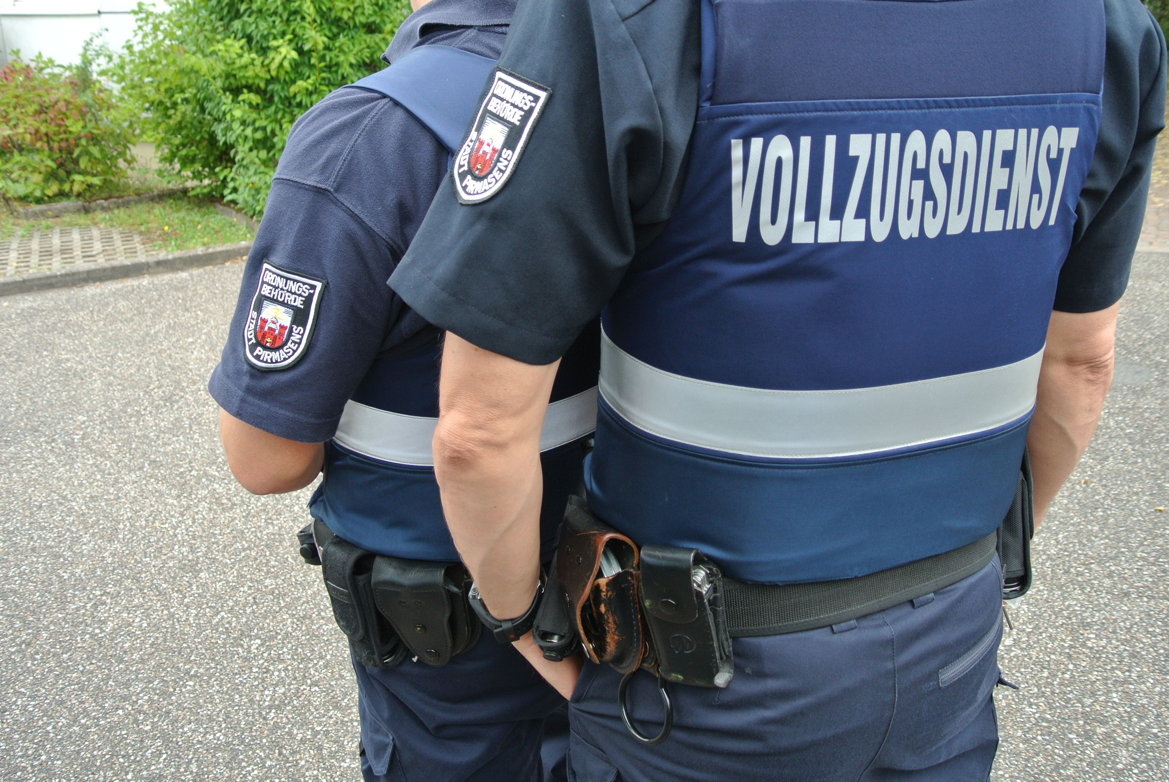 Zwei Personen vom Vollzugsdienst mit Uniform von hinten 