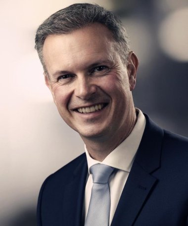 Portraitfoto von Bürgermeister Michael Maas vor neutralem Hintergrund im Anzug