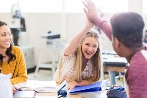 Schüler im Klassenraum geben sich Handschlag 