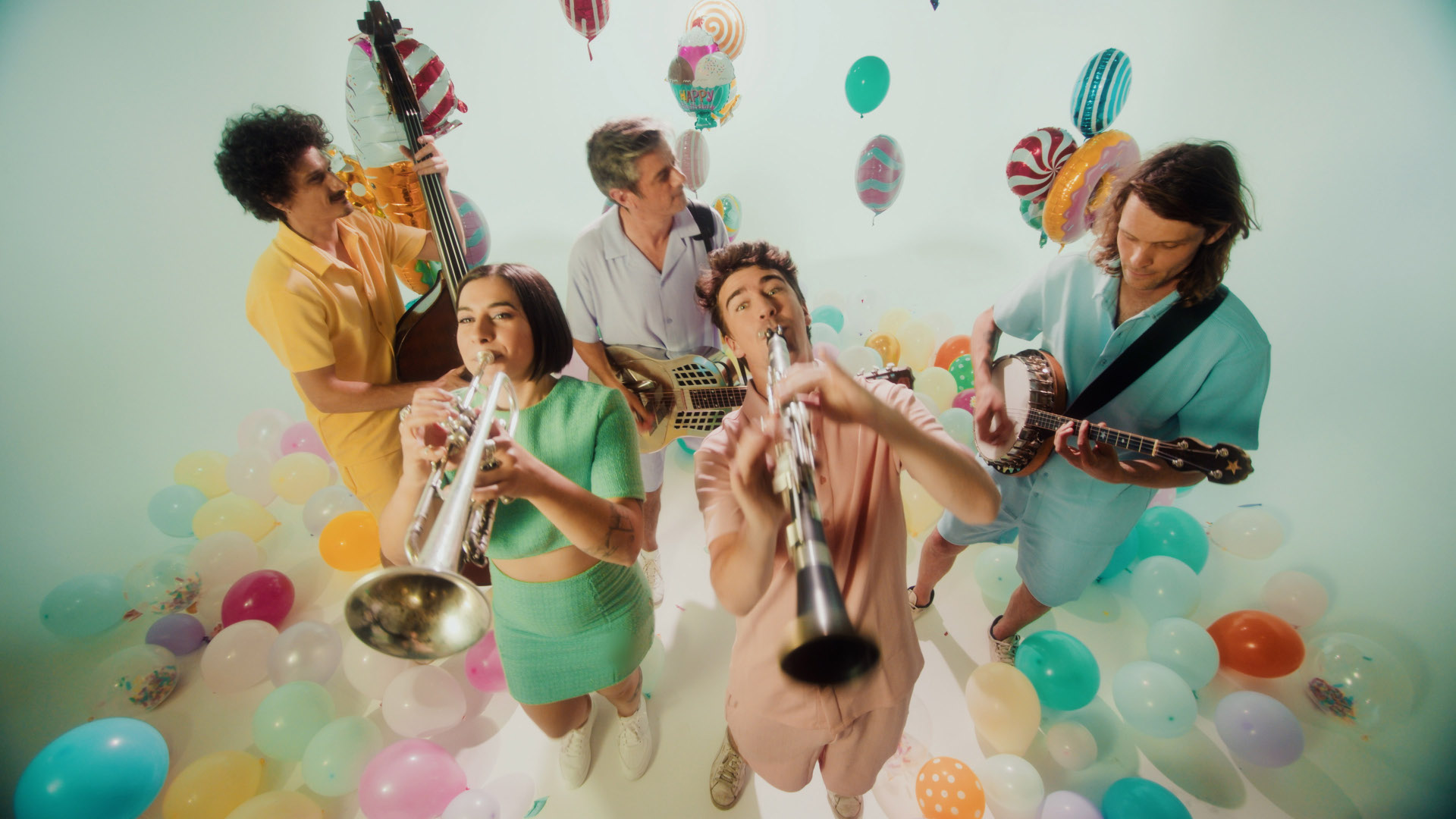 Neuer frischer Sound im alten Jazz und Blues mit den Mama Shakers beim Pirmasenser Sommerintermezzo Eine fröhliche Band spielt zwischen bunten Luftballons und Partydeko – zu sehen sind unter anderem Trompete, Klarinette, Kontrabass, Banjo und Resonatorgitarre in einer hellen Studio-Atmosphäre.