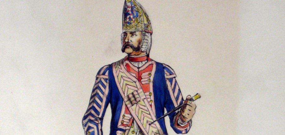 Fritz Kredel, einer der bedeutendsten Buchillustratoren des 20. Jahrhunderts, hat die landgräfliche Infanterie in Zeichnungen festgehalten – etwa hier den Tambour der 1. Leibkompagnie. Historische Illustration eines Tambours der „1. Leib-Kompagnie“ in farbenfroher Uniform mit Trommel und kunstvoll verziertem Helm. Die Zeichnung zeigt einen militärischen Musiker aus vergangener Zeit mit detaillierter Kleidung und traditioneller Ausrüstung.