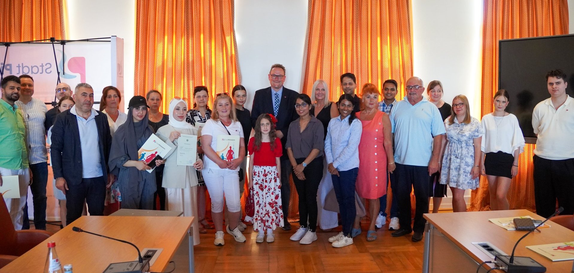 Einbürgerungszeremonie im Ratssaal Pirmasens Gruppenfoto einer Einbürgerungszeremonie im Ratssaal. Zu sehen sind neu eingebürgerte Bürgerinnen und Bürger gemeinsam mit Vertretern der Stadtverwaltung, darunter Oberbürgermeister Markus Zwick, bei der Übergabe von Urkunden und Dokumenten.