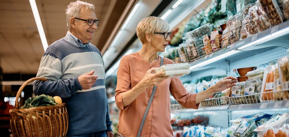 Mature husband and wife buying groceries in supermarket.