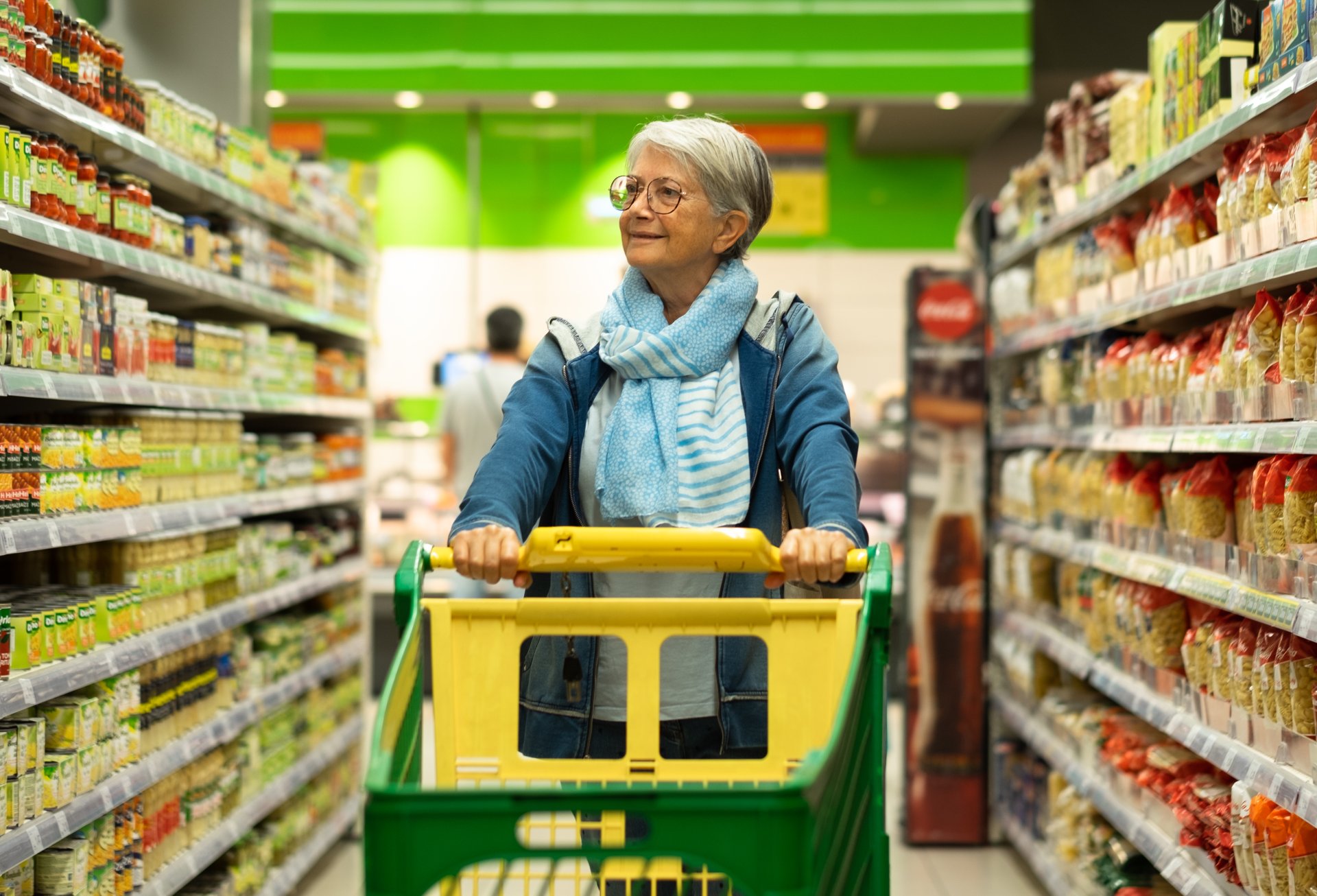 Retired senior woman pushing shopping trolley in supermarket sho Retired senior woman pushing shopping trolley in supermarket sho