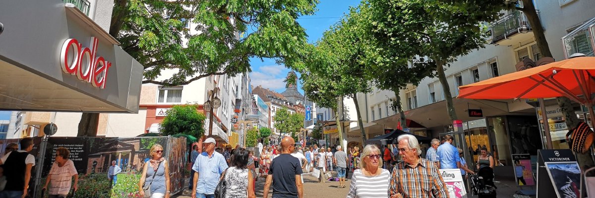 Fußgängerzone Nähe Wölfling. Fußgänger laufen durch die Stadt bei blauem Himmel
