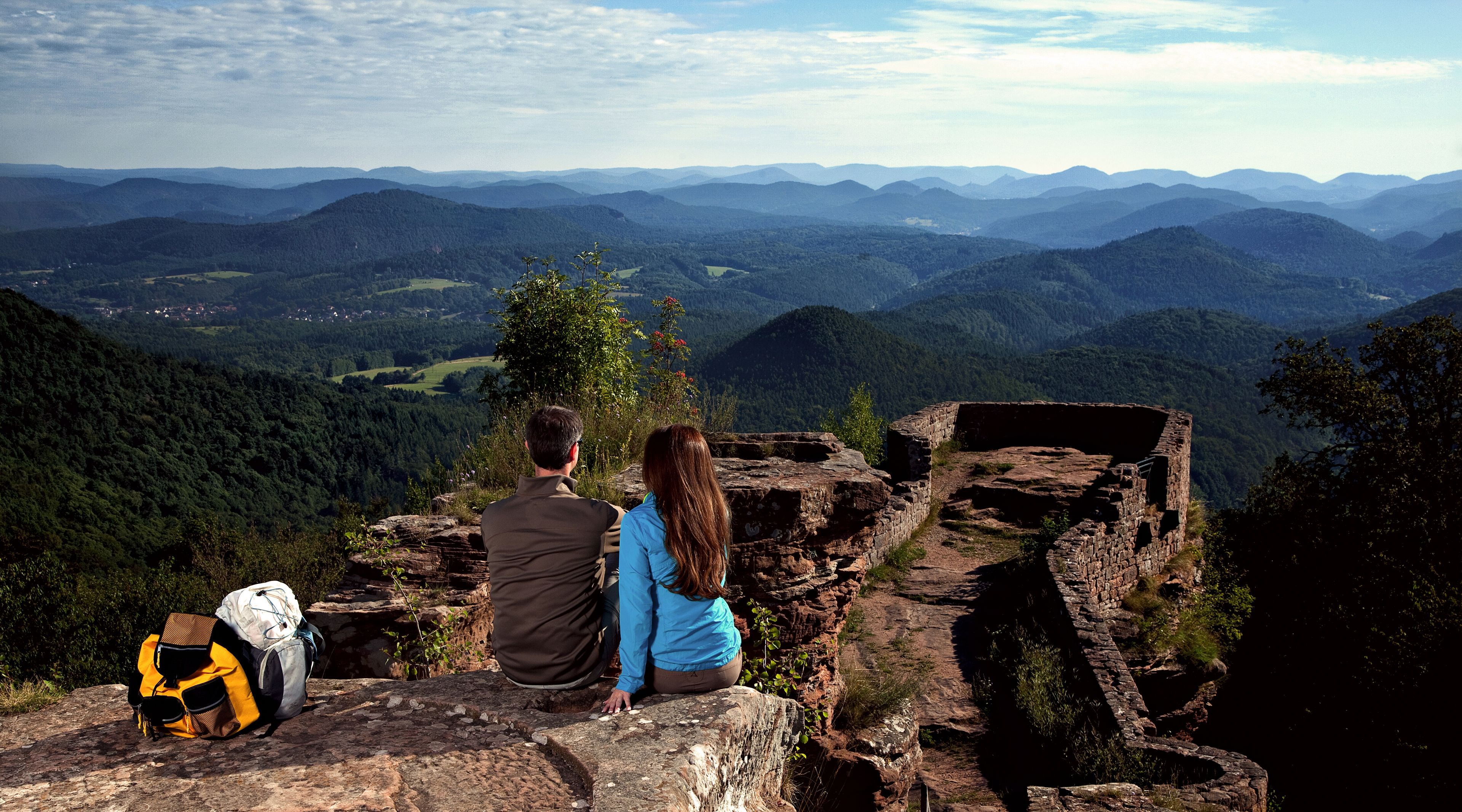 Zwei Wanderer sitzen auf Wegelenburg und genießen die Aussicht 