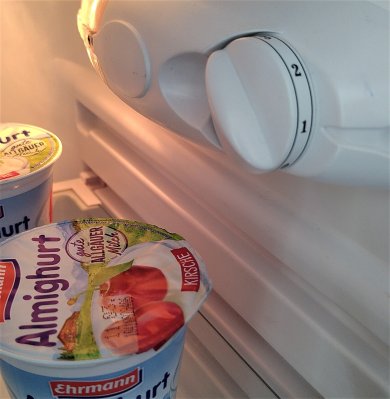 Kühlschrank von Innen in Nahaufnahme mit leuchtendem Licht und 2 Bechern Joghurt