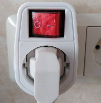 Stecker in einem Mehrfachstecker und oben ein Licht, welches anzeigt, ob der Mehrfachstecker angeschaltet ist oder nicht