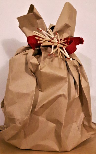 in braune Geschenktüte verpacktes Geschenk mit rotem Band und einem Strohstern