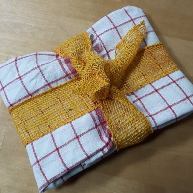 Geschenk ein ein weiß rotes Geschirrhandtuch eingepackt mit einer gelben Schleife